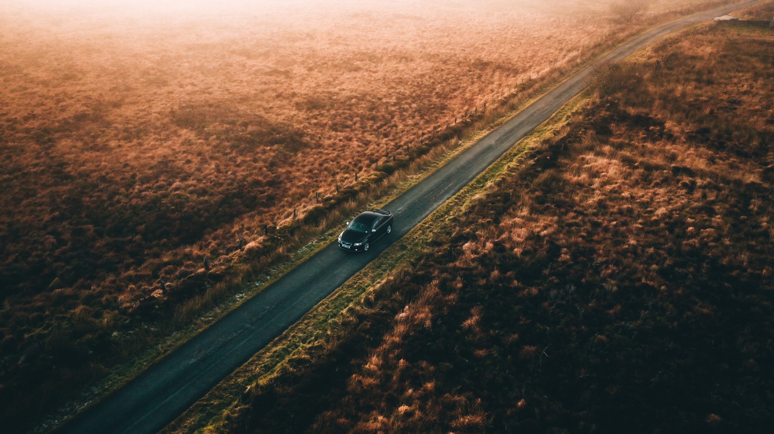 Car driving on long country road in sunset